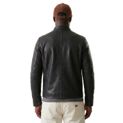 Men's black leather jacket back view with brown cap and cream pants