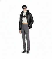Man wearing black leather jacket, Batman graphic turtleneck, gray trousers, and sunglasses