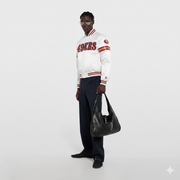 Man wearing white 49ers varsity jacket with red stripes, holding black leather bag, stylish streetwear look