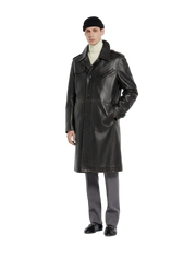 Men's black leather trench coat with classic collar and front buttons, styled with turtleneck and gray trousers