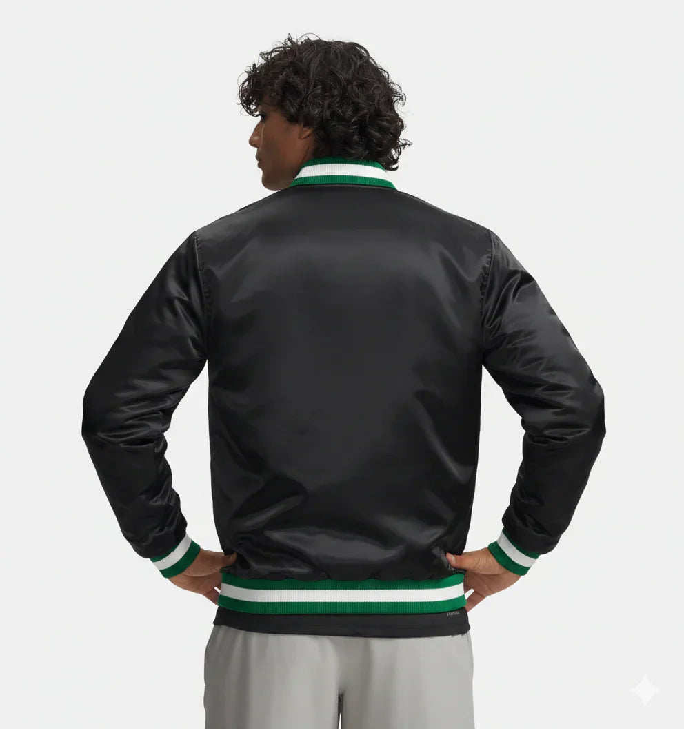 Black satin varsity jacket with green and white ribbed trim, worn by man with hands on hips