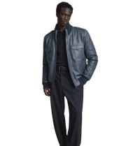 Man wearing stylish navy blue leather jacket with ribbed collar and front pockets, paired with dark pants.