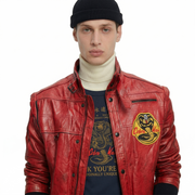 Red leather jacket with Cobra Kai patch, worn over graphic tee and turtleneck, styled with black beanie