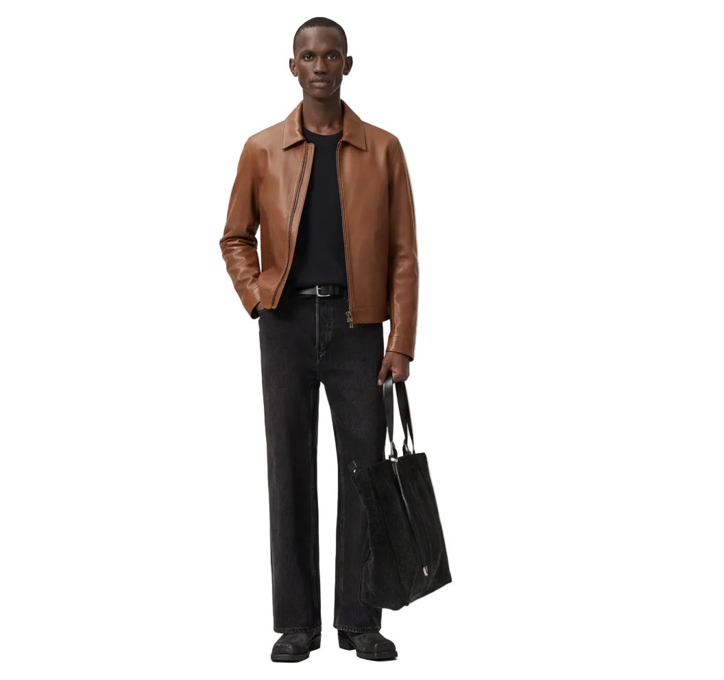 Man wearing a brown leather jacket and black pants holding a black bag on a white background