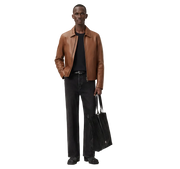 Man wearing brown leather jacket, black jeans, and carrying tote bag, stylish casual outfit