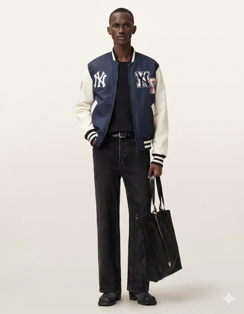 Men's navy and cream varsity jacket with NY logo, paired with black jeans and tote bag