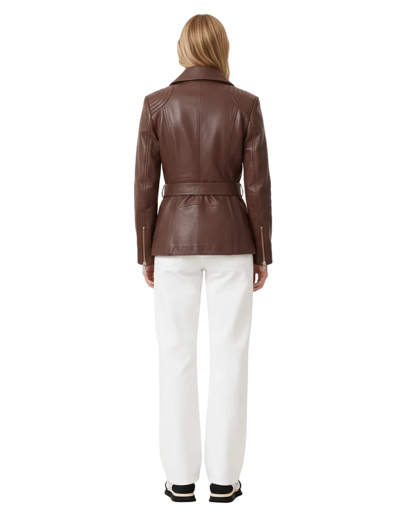Person wearing a brown leather jacket and white pants on a plain background