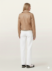 Tan leather moto jacket with zipper details, paired with white pants and sneakers, back view