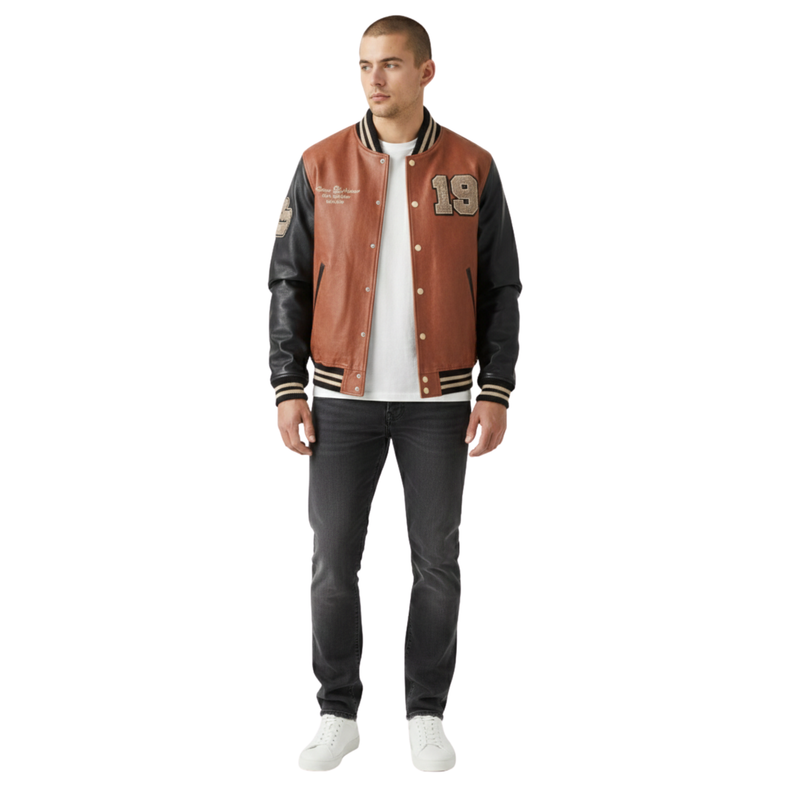 Premium men's full-leather varsity jacket by sam prime. Features a full-grain cognac brown leather body, black nappa leather sleeves, custom chenille patches, and striped rib-knit trim.
